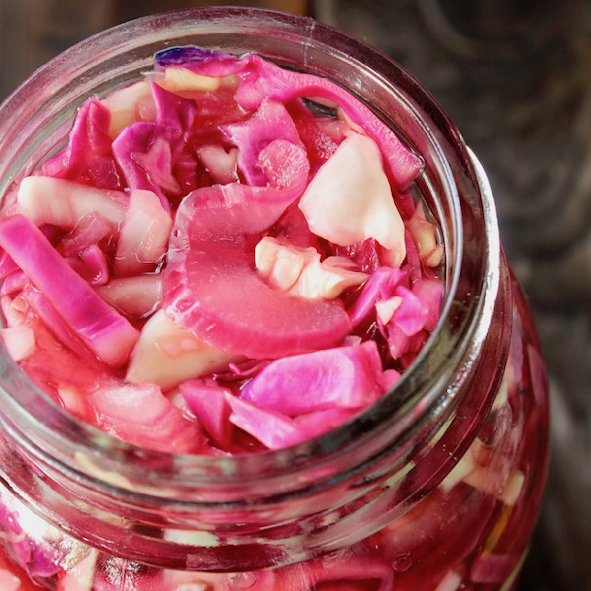 Top view of pink pickled cabbage in a Mason jar.