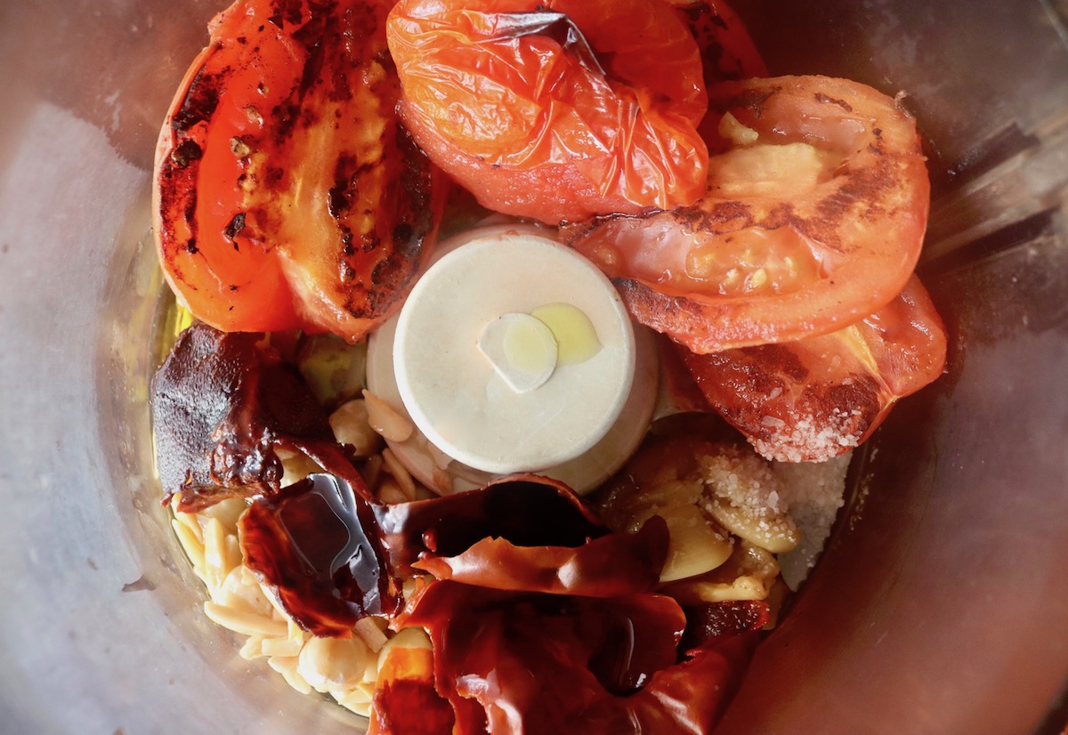 Tomatoes, hydrated red peppers, roasted garlic and oil in a food processor bowl.